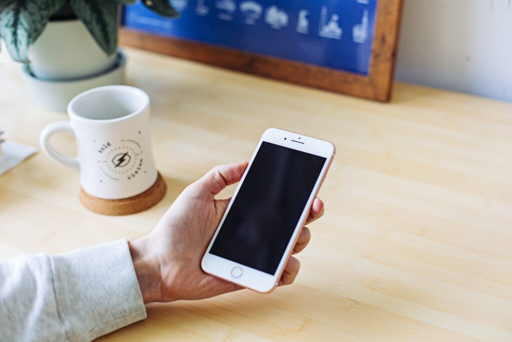 iPhoneを持つ手元とコーヒー